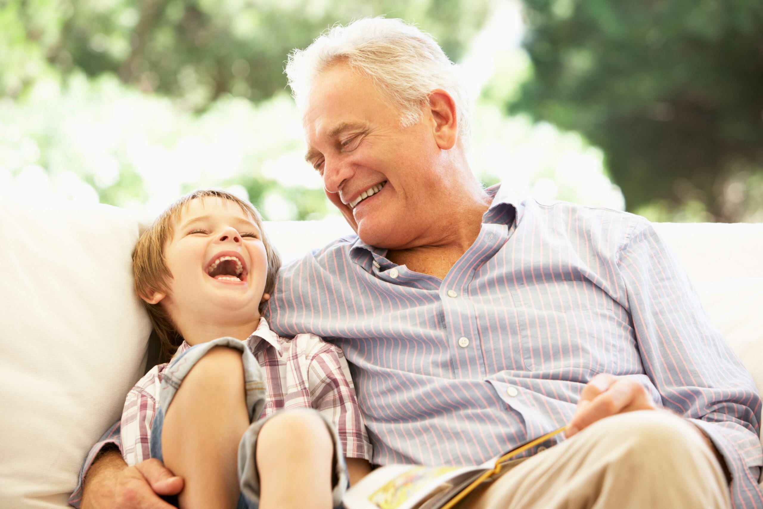 Close up image of grandfather sitting on a couch with grandson being able to hear clearly with a hearing device